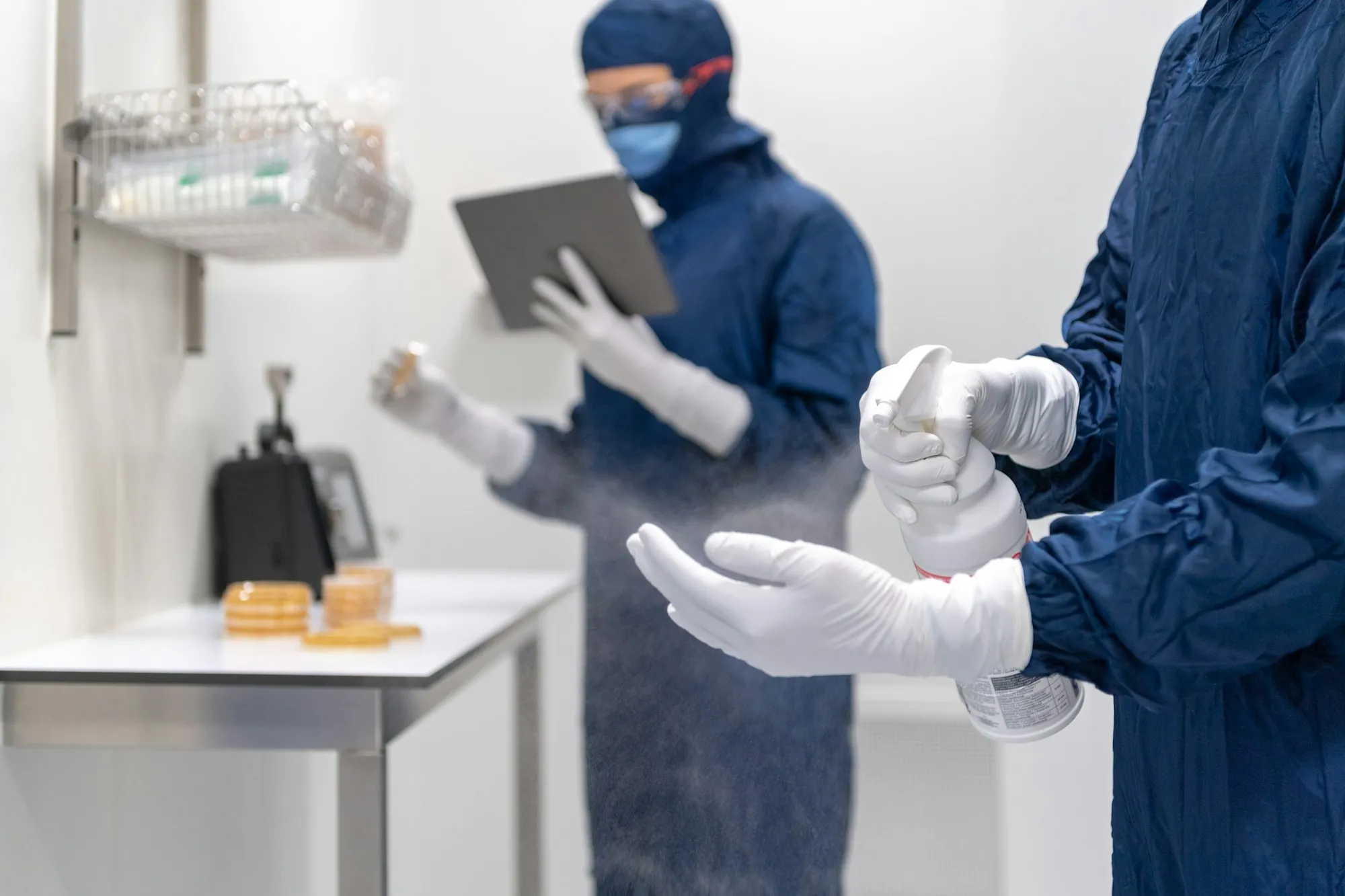 Workers in protective gear sanitizing a room