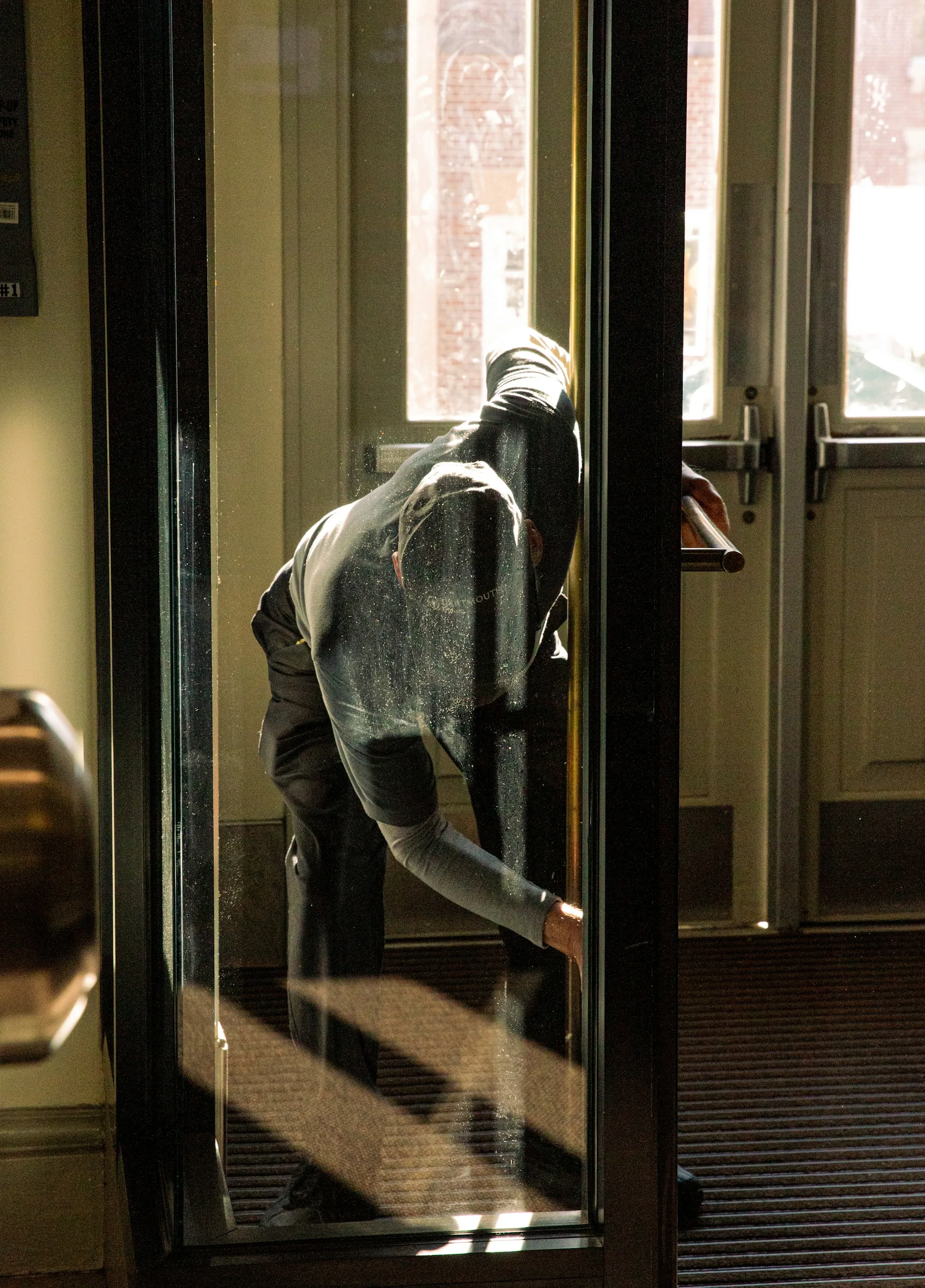 Cleaner wiping down a door frame at a building entrance